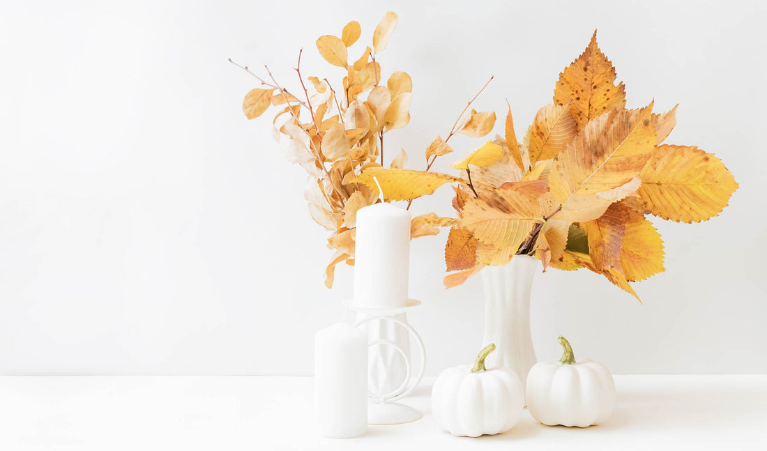 White candles and pumpkins with fall leaves 