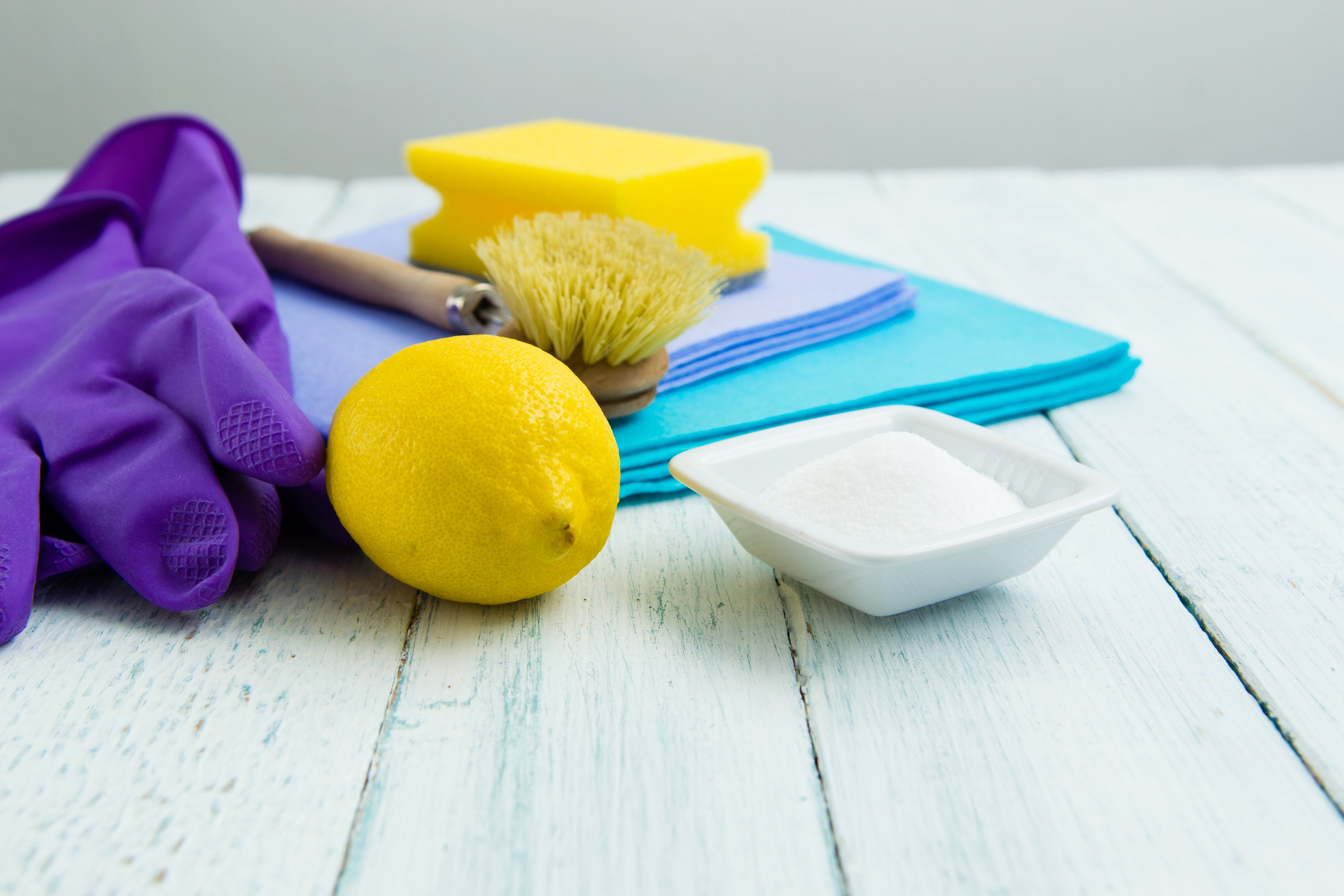 image includes lemon, citric acid, cleaning brush and sponge, with a purple glove