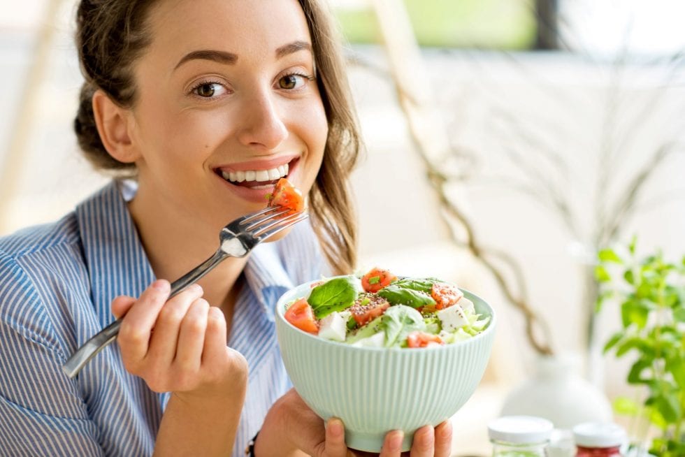 woman eating salad and smiling 