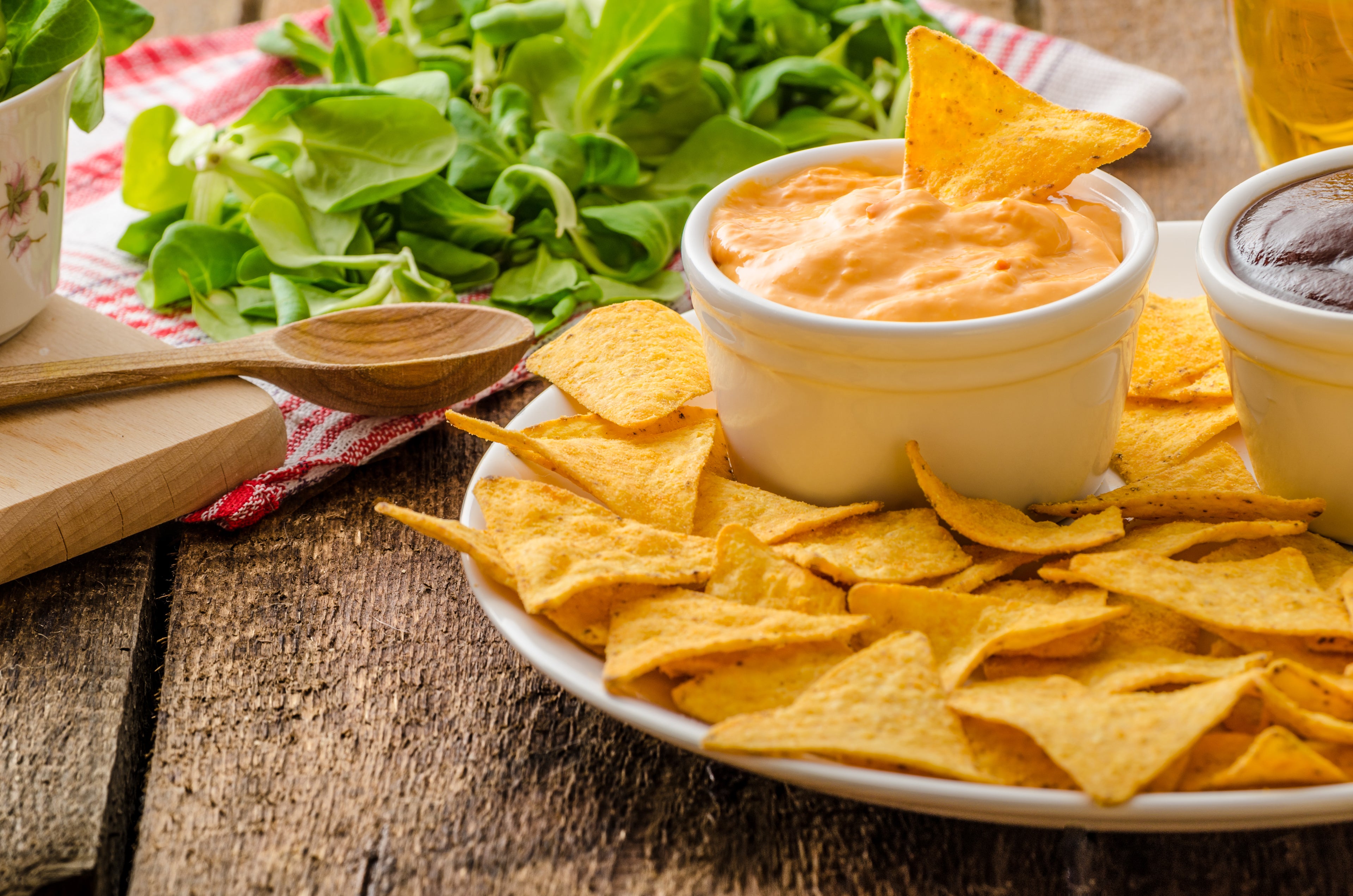 a tabletop with a bowl of chips and nacho cheese 